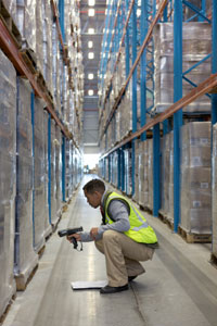 A warehouse worker uses a bar code scanner on pallets. A warehouse worker uses a bar code scanner on pallets.
